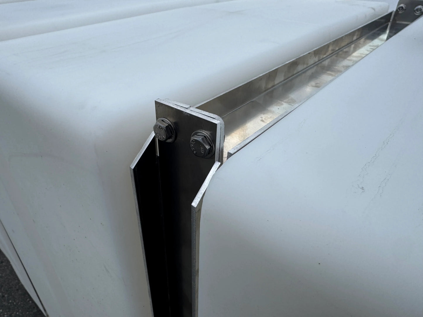 Close-up of softwash equipment with metal brackets and bolts securing white tank panels