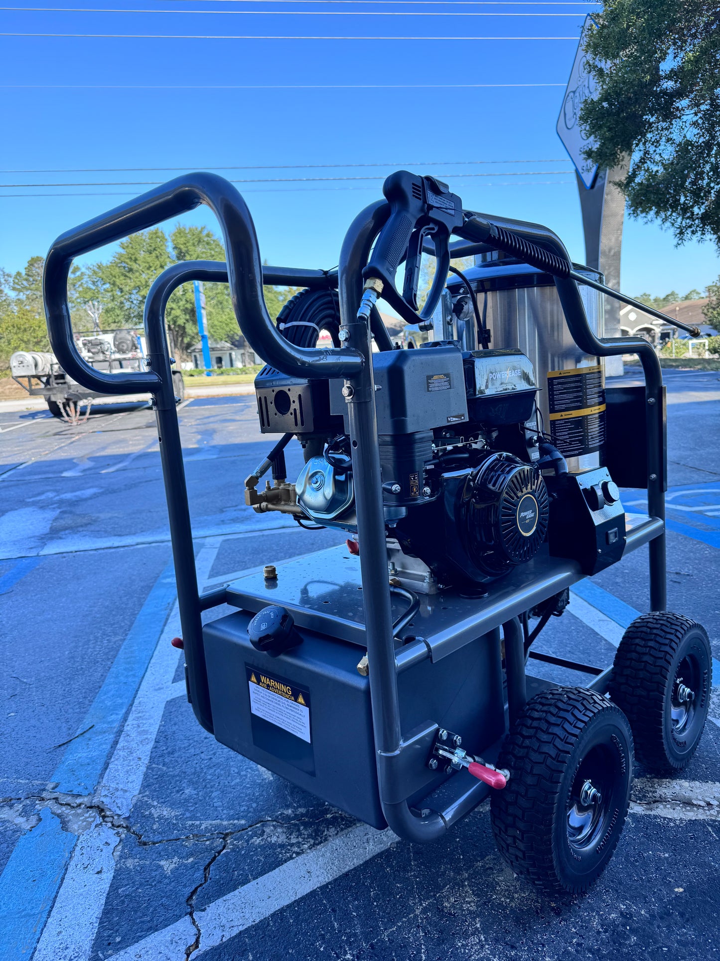 Pressure washer on wheels in a parking lot with clear blue sky
