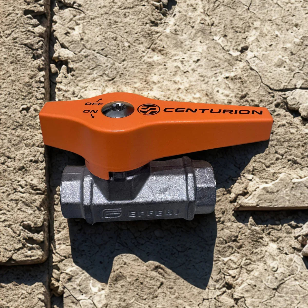 Orange Centurion ball valve for softwash equipment on concrete surface