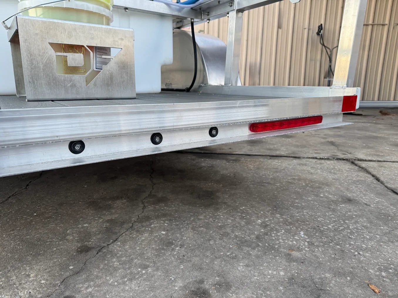 Aluminum softwash trailer with red safety lights and mounted chemical tanks for professional cleaning equipment