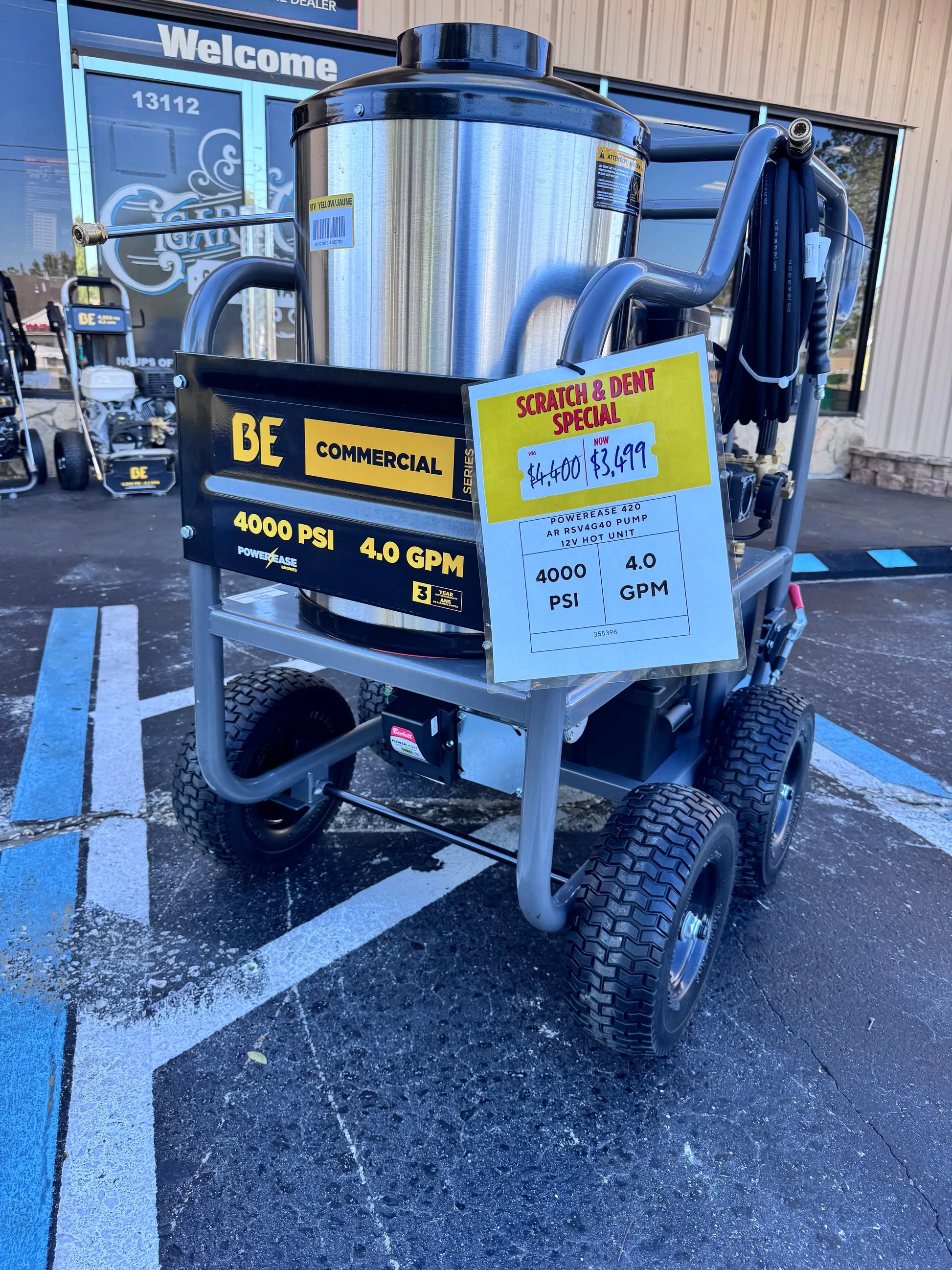 Commercial pressure washer with a scratch and dent sale sign in a parking lot.