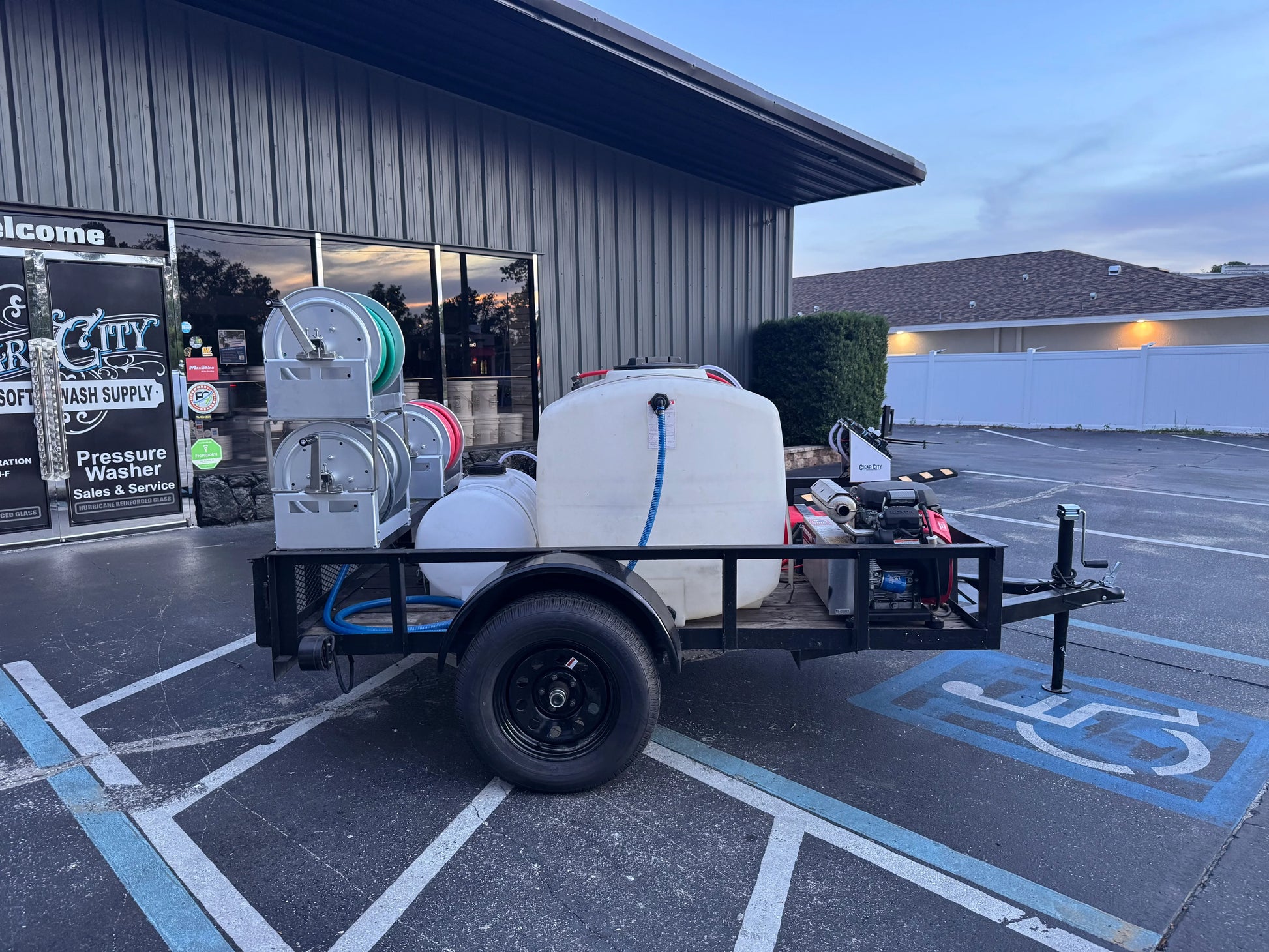 Softwash equipment trailer with tanks and hoses parked outside a supply store