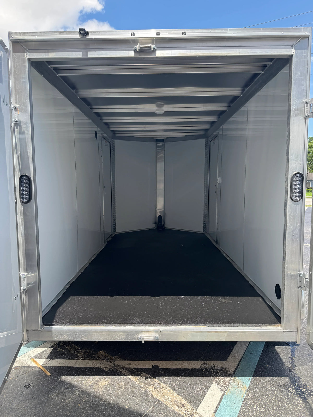 Empty aluminum softwash equipment trailer with LED lights and black flooring, ready for transport.