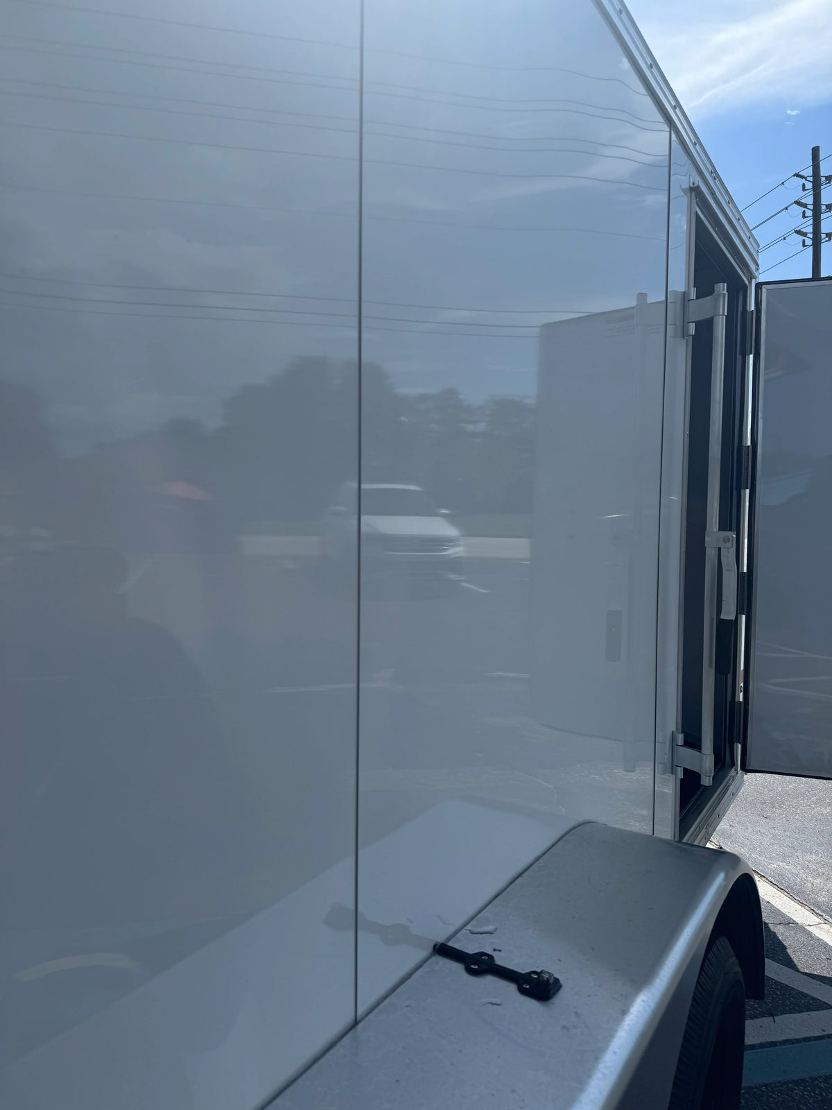 White softwash equipment trailer with open rear doors under clear sky