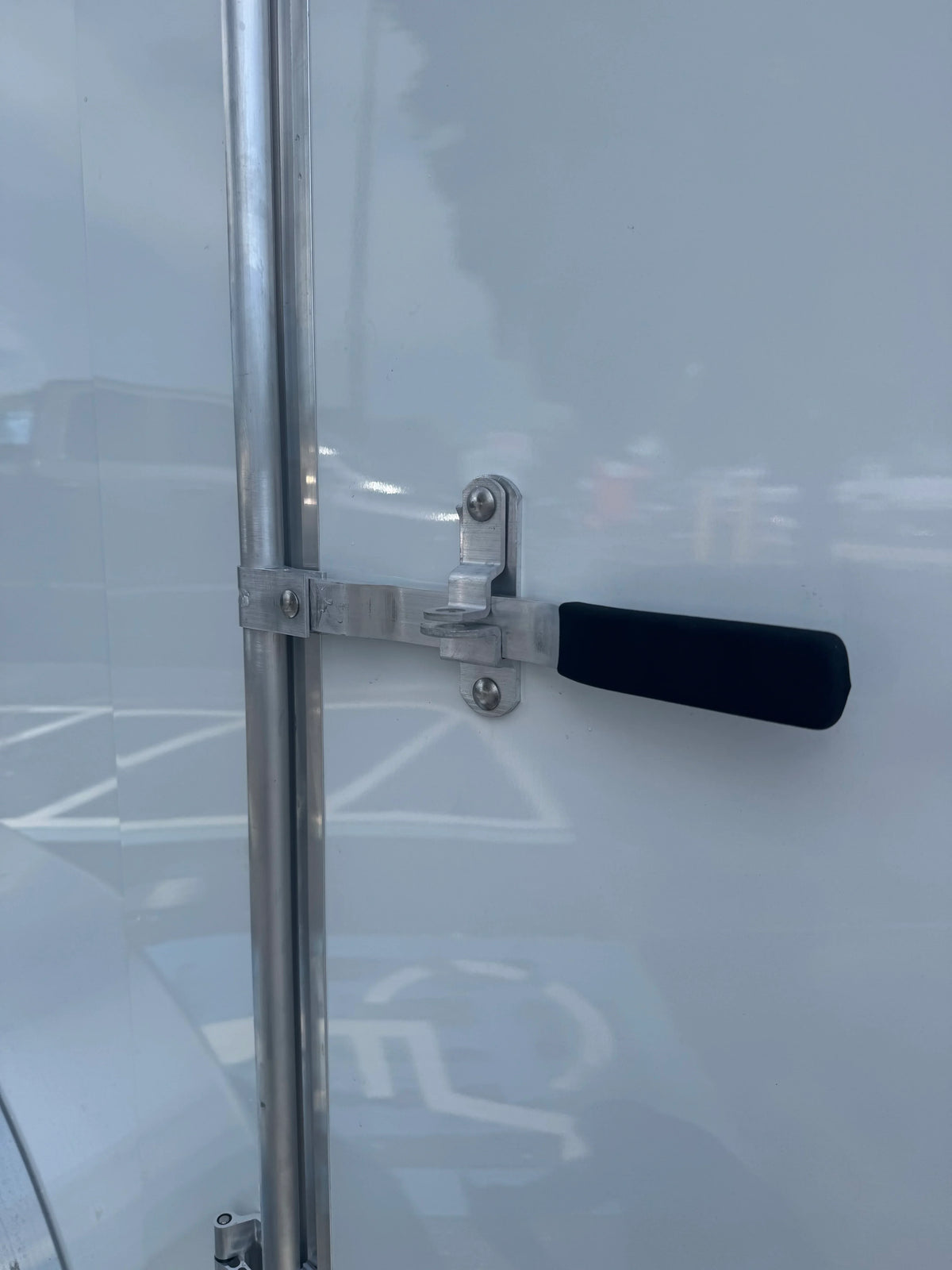 Sturdy metal latch with black handle on white softwash equipment door