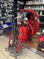 Red softwash equipment with coiled hoses and cleaning supplies in a store